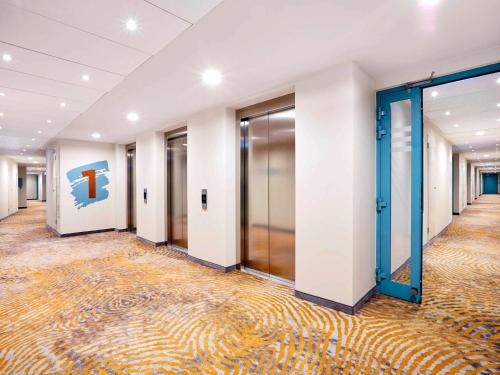 a corridor of an office building with doors and a carpet at ibis Styles Kraków Centrum in Krakow