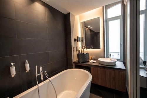 a bathroom with a bath tub and a sink at Best Western Premier Le Chapitre Hotel and Spa in Remiremont