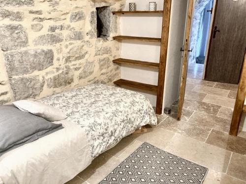 een bed in een kamer met een stenen muur bij Maison de 3 chambres avec piscine partagee jardin clos et wifi a Saint Andre de Cruzieres in Saint-André-de-Cruzières