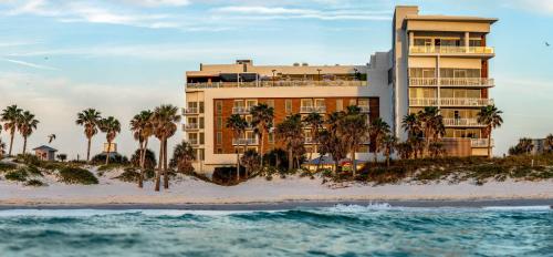 ein Hotel am Strand mit Palmen und dem Meer in der Unterkunft The Hiatus Clearwater Beach, Curio Collection By Hilton in Clearwater Beach