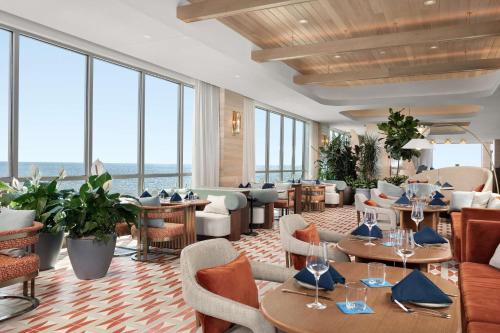 un restaurante con mesas, sillas y ventanas grandes en The Hiatus Clearwater Beach, Curio Collection By Hilton, en Clearwater Beach