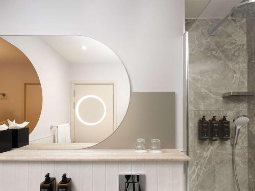 uma casa de banho com um espelho e um chuveiro em Mercure London Earls Court em Londres
