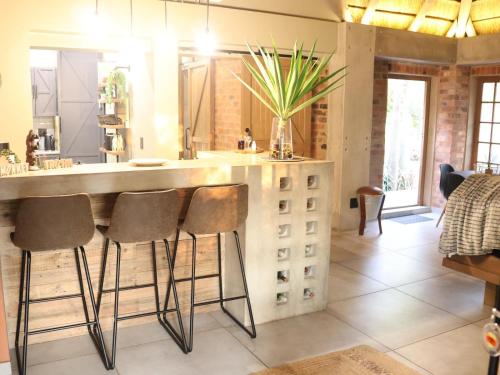 a kitchen with a counter with stools and a bar at Monkey Thorn in Roodeplaat