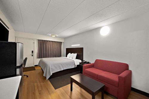 a hotel room with a bed and a red couch at Suburban Studios Peoria in Peoria