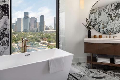 a bathroom with a white tub and a window at Thompson Houston, by Hyatt in Houston
