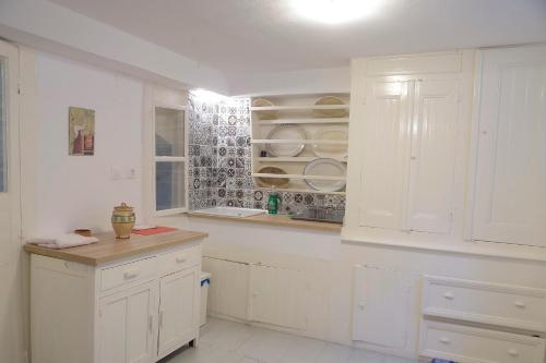 a white kitchen with white cabinets and a counter at Soultana's Antique House in Plomarion