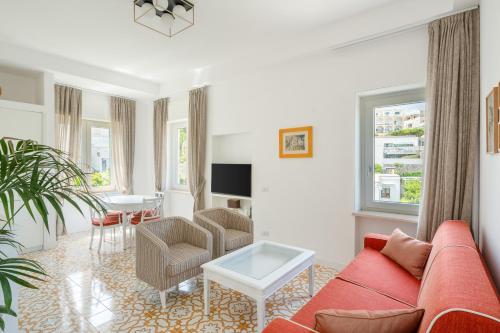Casa Levante Luxury Apartments Capri في كابري: غرفة معيشة مع أريكة حمراء وطاولة