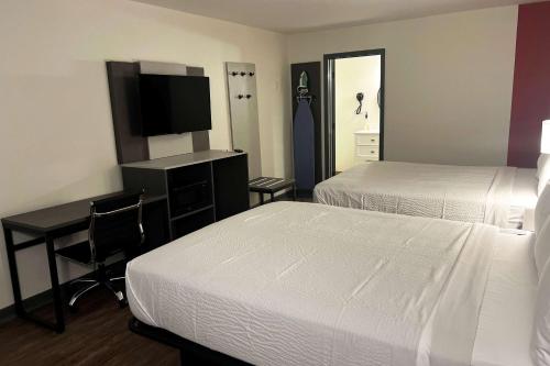 Habitación de hotel con 2 camas y escritorio con TV. en Ramada by Wyndham Bainbridge, en Bainbridge