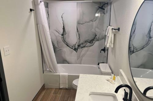 a bathroom with a shower curtain and a toilet and a tub at Ramada by Wyndham Bainbridge in Bainbridge