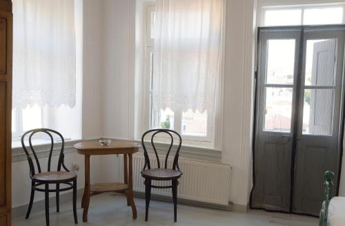two chairs and a table in a room with a window at Soultana's Antique House in Plomarion