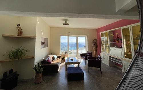 a living room with couches and chairs and a large window at Art and Nature Apartment in Sellía