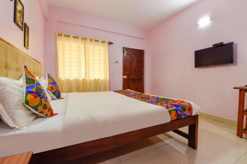FabExpress Morjim Paradise في مورجيم: غرفة نوم مع سرير وتلفزيون على الحائط