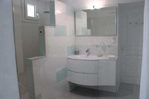a white bathroom with a sink and a mirror at chambre d'hôte au calme absolu in Lectoure