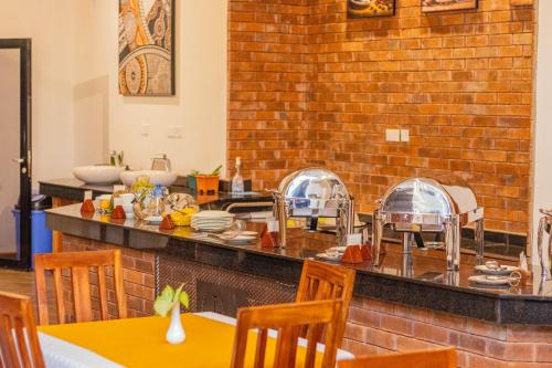 a restaurant with a counter with plates and dishes at Desert Rose Resort Kisumu in Kisumu