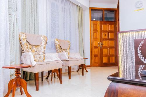 a living room with two chairs and a television at Desert Rose Resort Kisumu in Kisumu