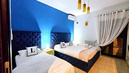 two beds in a room with a blue wall at Center Apartment Easy_Luxury in Tirana