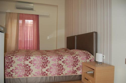a bedroom with a bed with a pink blanket and a dresser at Filoxeno in Ermoupoli