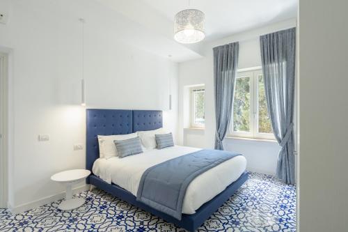 a bedroom with a blue and white bed and a window at Casa Levante Luxury Apartments Capri in Capri