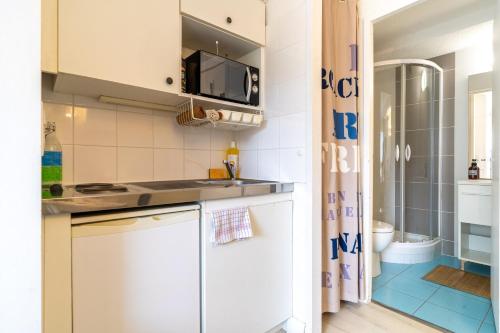 eine kleine Küche mit weißen Schränken und einer Dusche in der Unterkunft Le Seafront - Charmant studio in Arcachon