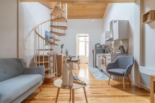 un salon avec un canapé et un escalier en colimaçon dans l'établissement La Thibaudière - Appt en centre-ville, à Arcachon