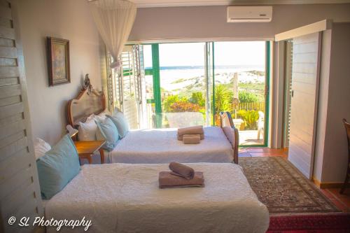 a hotel room with two beds and a balcony at 14 Penguin Place, Melkbosstrand in Melkbosstrand