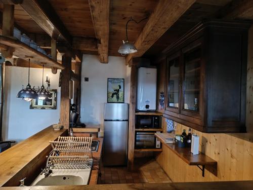 une cuisine avec un réfrigérateur en acier inoxydable et des armoires en bois dans l'établissement Maison/Vacances/Montagne, à Fontanges