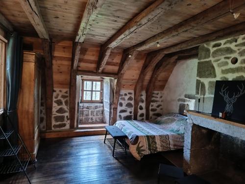 - une chambre avec un lit dans une pièce dotée d'une cheminée dans l'établissement Maison/Vacances/Montagne, à Fontanges