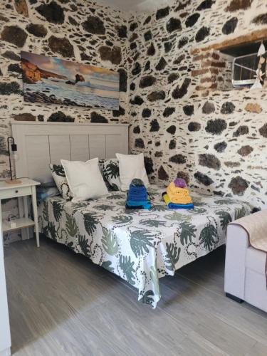 1 dormitorio con 1 cama en una pared de piedra en Casa Noda Tarajalejo en Tarajalejo