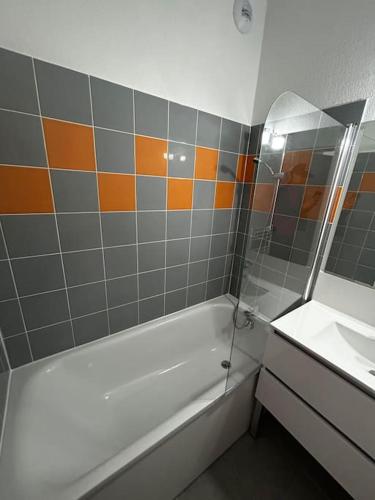 une salle de bain avec une baignoire, un lavabo et un miroir dans l'établissement Le Saint Quentin, à Juvignac