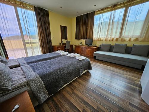 a bedroom with a bed and a couch and windows at Family Hotel Komhotel in Berkovitsa