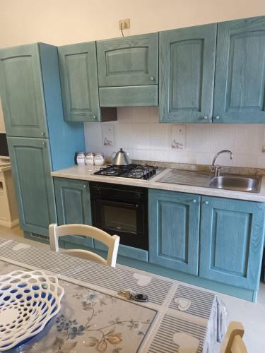 a kitchen with green cabinets and a sink and a table at Villa del Papiro Charme Apartments in Avola