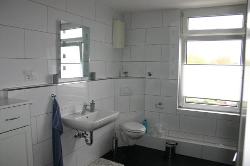 a white bathroom with a sink and a toilet at Appartment Herten - Auch zur EM 2024 Arena AufSchalke in Herten