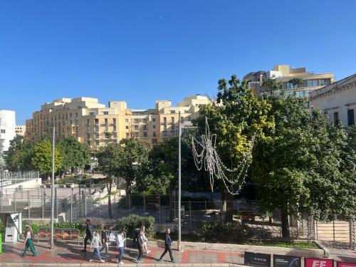 un grupo de personas caminando por una acera en una ciudad en Stresa Court Apartments, en San Julián