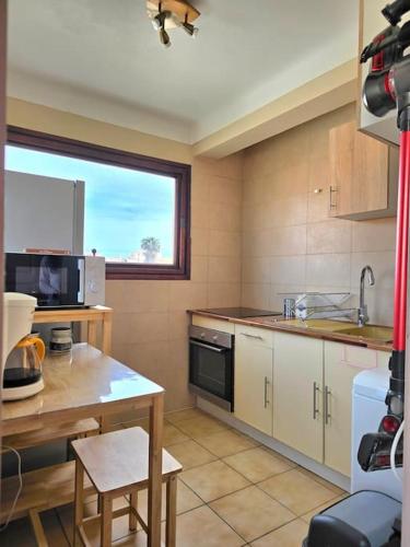 une cuisine avec une table, un évier et une fenêtre dans l'établissement Hibiscus - plage avec Parking - climatisé - wifi, à Canet