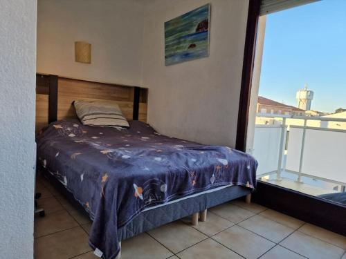 Ce lit se trouve dans un dortoir avec vue sur un balcon. dans l'établissement Hibiscus - plage avec Parking - climatisé - wifi, à Canet