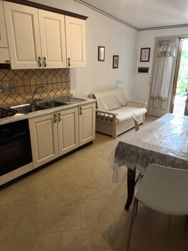 a kitchen with white cabinets and a table and a couch at Villa del Papiro Charme Apartments in Avola