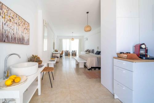una cucina bianca con lavandino e un soggiorno di Alpha Urban Suites a Città di Rodi