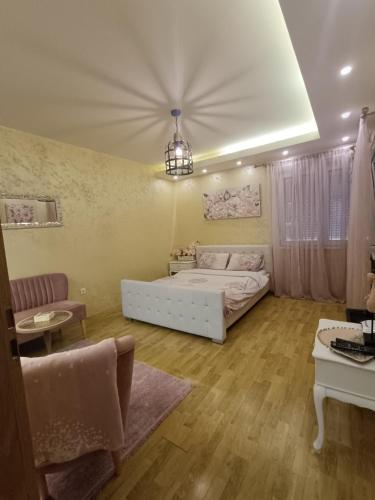 sypialnia z białym łóżkiem i żyrandolem w obiekcie Apartman Golden Rose w mieście Loznica