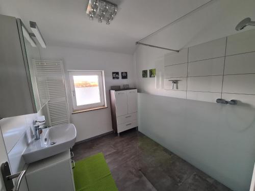 a white bathroom with a sink and a mirror at Wolke7 in Erbach