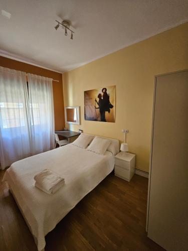 um quarto com uma cama grande e um quadro na parede em El Vasco Rooms em Oviedo