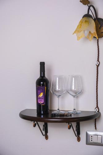 a bottle of wine on a shelf with two wine glasses at Funtana'e Mari in Gonnesa