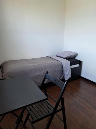 une chambre avec un lit, une chaise et une table dans l'établissement Chambre Solo Duo 20 min Paris, à Drancy