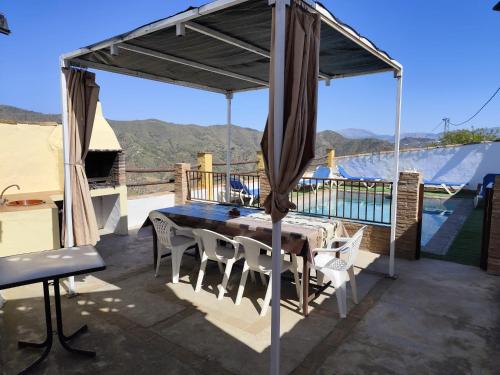 een tafel en stoelen onder een luifel op een patio bij Casa Villazo II in Almáchar