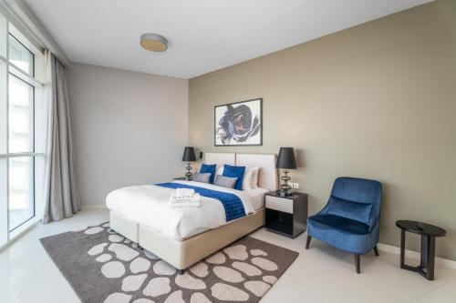 a bedroom with a bed and a blue chair at Nasma Luxury Stays - Charming Studio at DAMAC Hills Artesia Tower C in Dubai