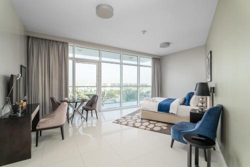 a bedroom with a bed and a table and chairs at Nasma Luxury Stays - Charming Studio at DAMAC Hills Artesia Tower C in Dubai