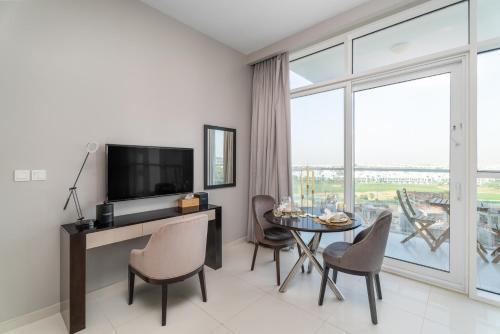 a living room with a television and a table with chairs at Nasma Luxury Stays - Charming Studio at DAMAC Hills Artesia Tower C in Dubai
