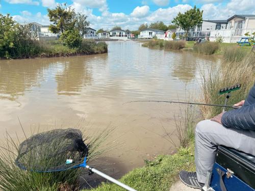 un homme est assis sur un bateau pour pêcher sur une rivière dans l'établissement Holidays with TLC at Cherry Lea Park, à Skegness