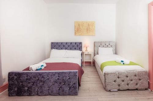 een slaapkamer met 2 bedden en een poef bij Warm&Welcoming City Centre Apartments by Meadows 11 in Edinburgh
