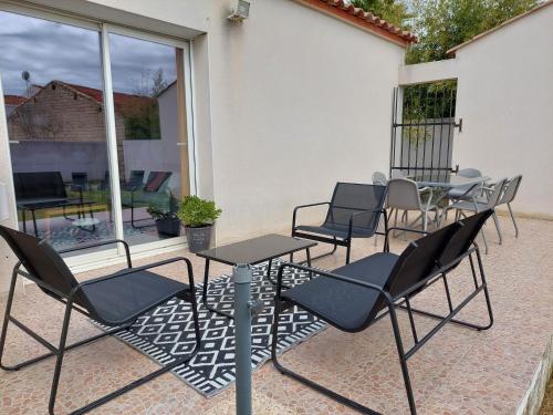 een groep stoelen en tafels op een patio bij CHARMANTE MAISON 4/6 PERSONNES in Saint-Aunès