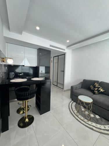 阿克拉的住宿－Deluxe Studio Apartments at Kass Towers Accra - Upper Floor By VP Properties，厨房以及带沙发和桌子的客厅。